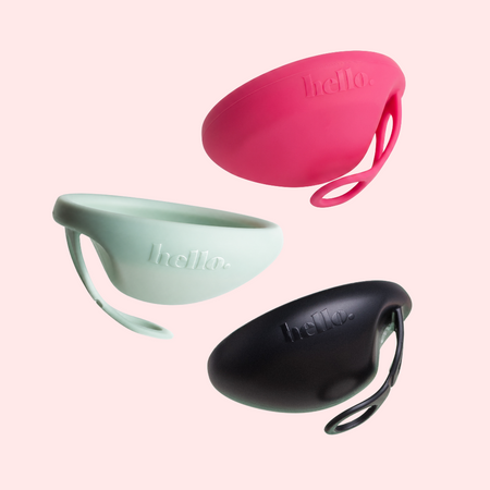Pink, Blue and Black coloured menstrual discs on a light pink background