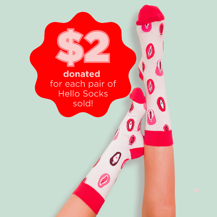 Legs against a green wall wearing socks with vulva illustrations with a graphic logo stating $2 donated from each pair sold.