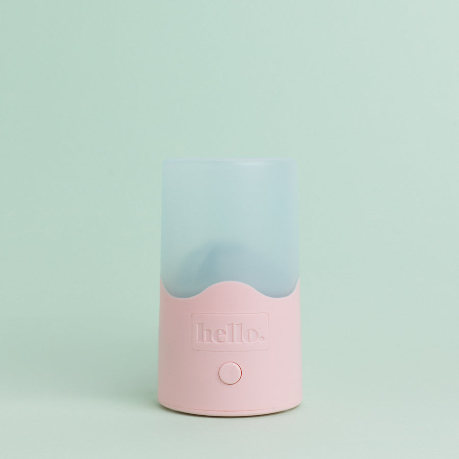 A compact pink and blue Hello Steamy menstrual cup and disc sterilizer with a clear upper section and a pink base, featuring the 'Hello' brand name.