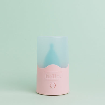 Steam steriliser with pink base and frosted blue lid against a pastel green background