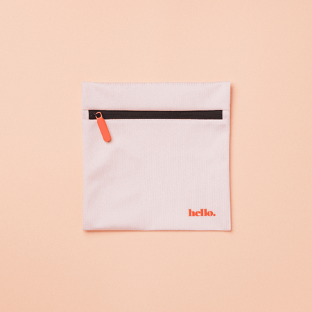 A pale pink waterproof storage bag with a black zipper and the word 'hello' printed in red on the front. The bag is displayed against a plain peach background.