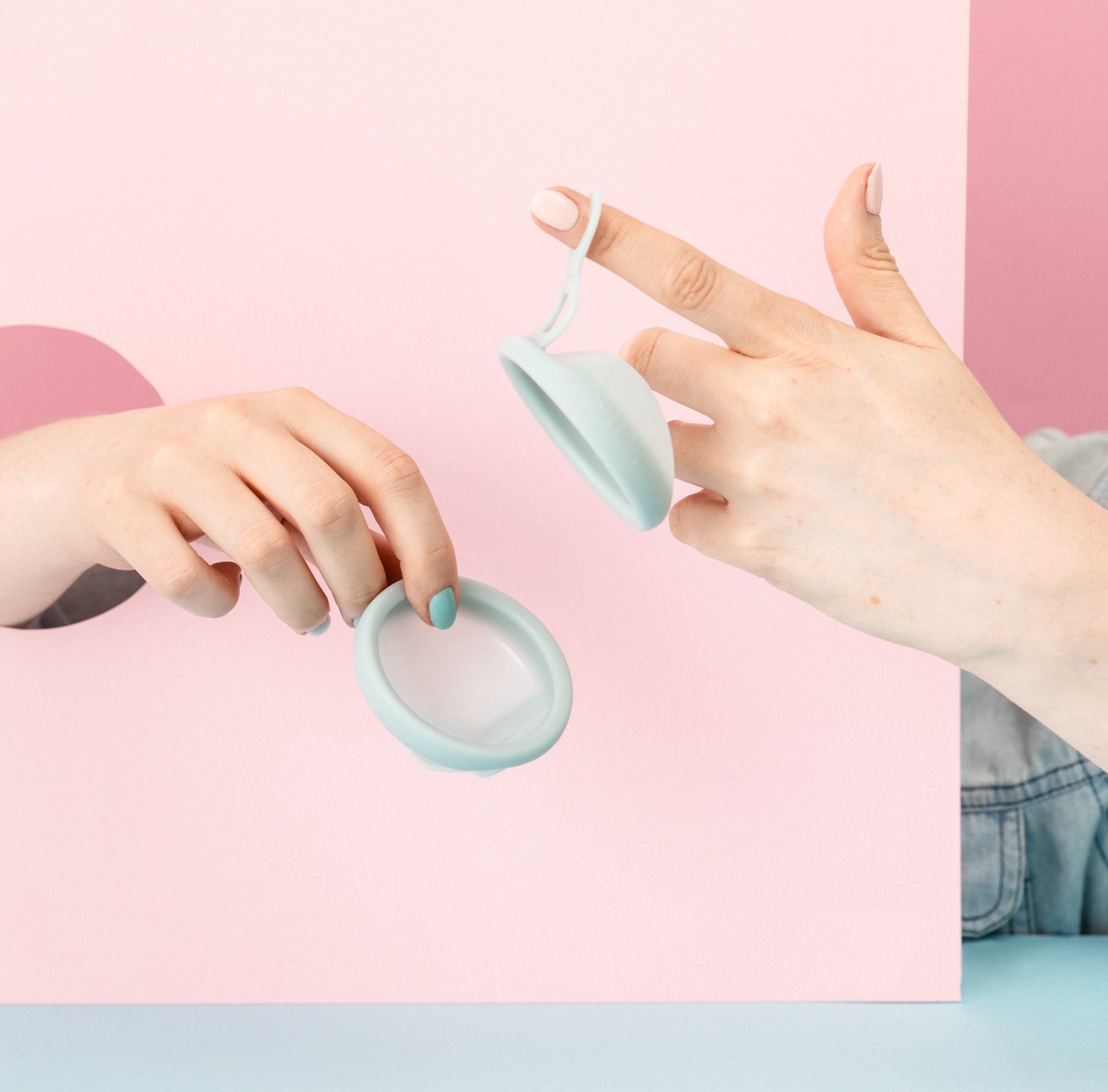 Two hands holding menstrual discs 