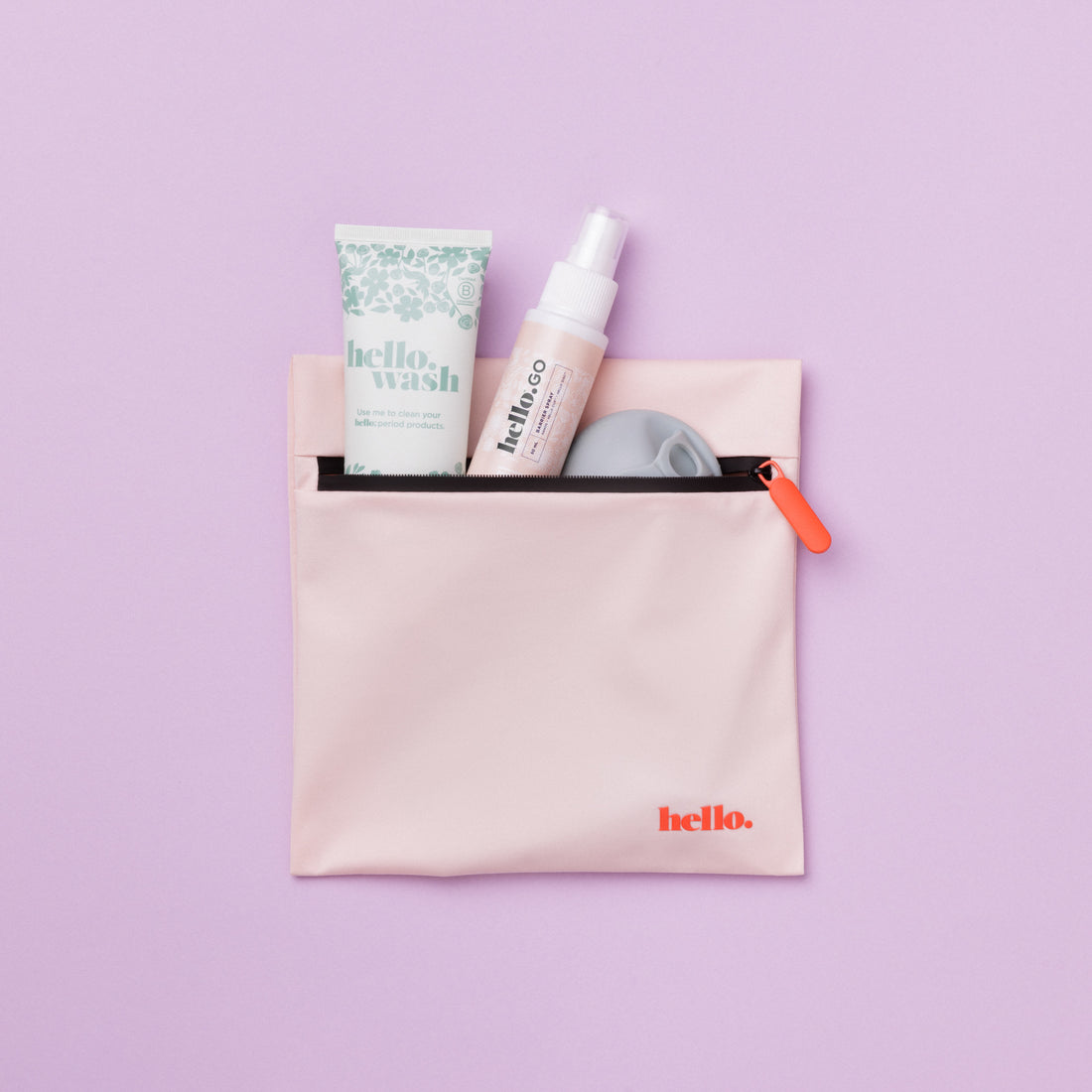 Pink waterproof bag with blue floral tube, small spray bottle and menstrual disc emerging from inside against a lilac backdrop