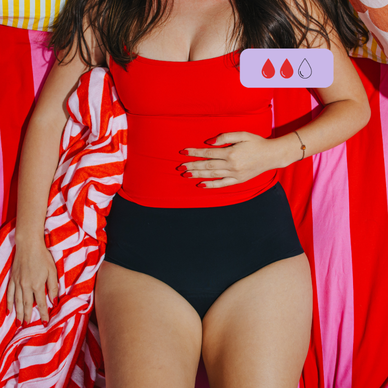 Person wearing a red top and black high waist period underwear against a colorful striped background