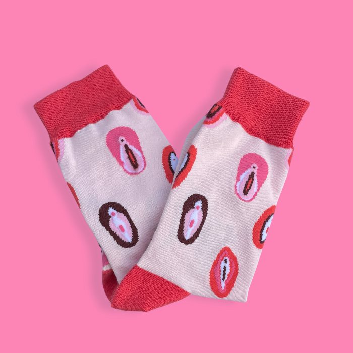 Folded socks with vulva illustration on them on a pink background