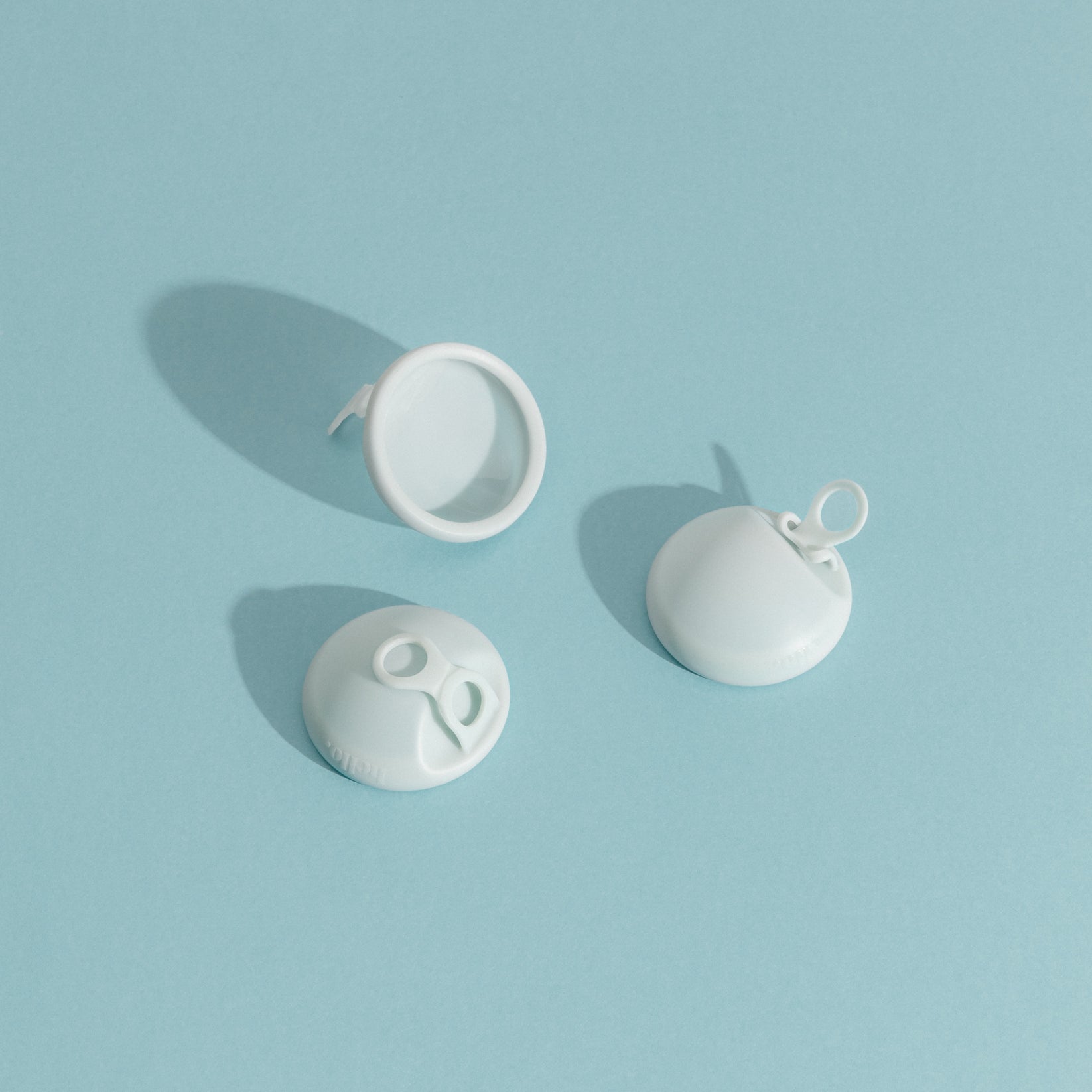 three menstrual discs on a blue background