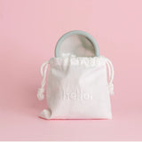 Hello Disc menstrual disc in sea fog coming out of a drawstring cotton bag with pink background.